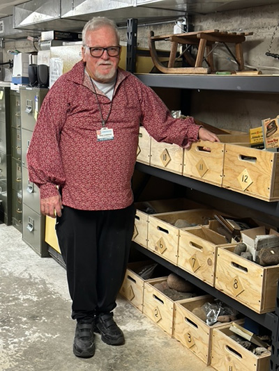 Dick standing next to some boxes on shelves